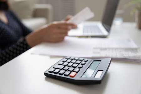 Crop close up of calculating machine lying on table, provident economical woman manage finances...