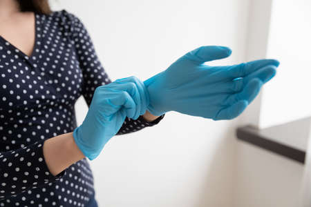 Crop close up of woman wear protective rubber gloves against covid-19 contagious epidemics, female try medical gear protecting from corona virus outbreak, coronavirus pandemics, health conceptの写真素材