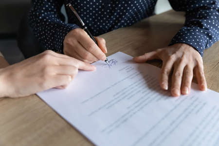 Close up young indian woman putting signature on hiring contract, multiracial female client...