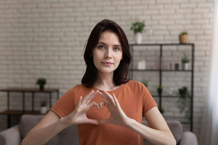 Headshot portrait of young Caucasian woman show heart love sign gesture express gratitude and care,...