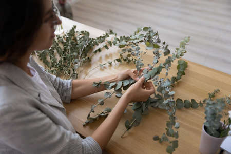 Top above view focused young female florist involved in creating handmade house interior decorations...