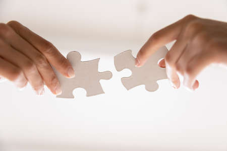 Close up of people assemble jigsaw puzzle find business solution or perfect match. Diverse employees workers put join pieces, participate in teambuilding activity. Teamwork, collaboration concept.の写真素材