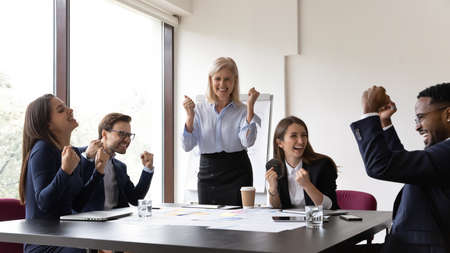 Excited multiracial colleagues celebrate business shared team success at meeting in office....
