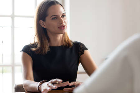 Confident Caucasian young female job candidate or applicant talk discuss ideas at work interview in...