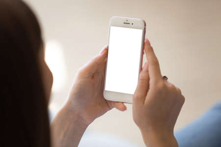 Close up of Young woman using smartphone with empty white mock up screen left for copy space. Client...