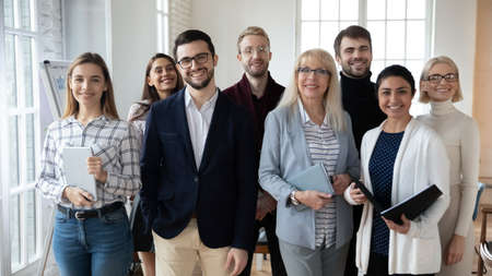 Portrait of smiling diverse team posing together in office show unity and support at workplace....