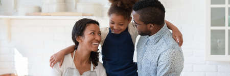 Horizontal photo banner of happy young african american biracial couple parents holding small adorable kid girl on hands, enjoying spending weekend leisure time in kitchen, website header designの写真素材