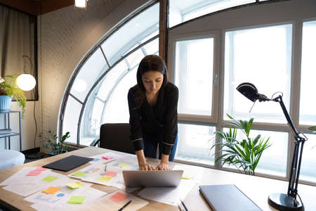 Concentrated young indian ethnicity businesswoman employee using computer application, organizing workflow with creative approach alone in modern office room, current issues or tasks management.の写真素材