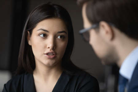 Close up head shot serious young indian ethnicity businesswoman talking to male confident partner,...