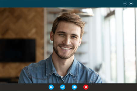 Close up headshot portrait screen view of smiling young Caucasian man look at camera have webcam conference. Happy male speak talk on video call from home, engaged in virtual digital web event.の写真素材