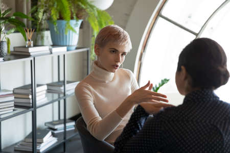 Concentrated multiethnic female colleagues sit in office talk discuss business ideas together....