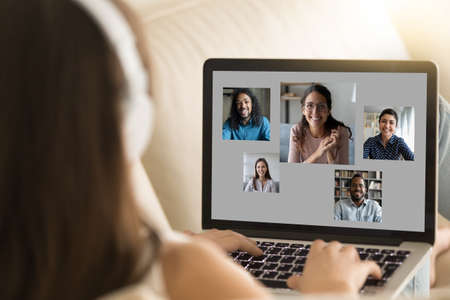 Close up rear view woman talking with diverse colleagues by video call, business people on laptop...