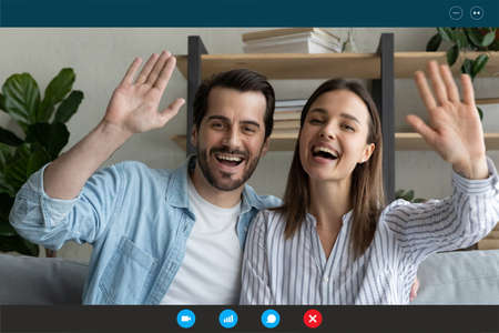 Head shot portrait screen view overjoyed couple waving hands at camera, greeting friends or...