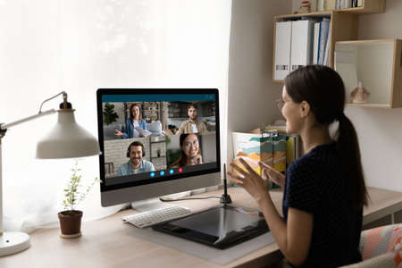 Rear view businesswoman chatting with colleagues online, business partners negotiations, using...