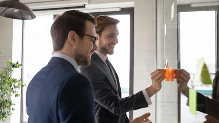 Side head shot view smiling young male successful employees colleagues in formal wear planning...