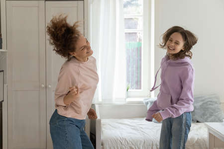 Happy loving mother have fun dance listen to music with teenage daughter in home children bedroom. Excited overjoyed mom and 13s teenager daughter enjoy lazy funny leisure weekend together.の写真素材