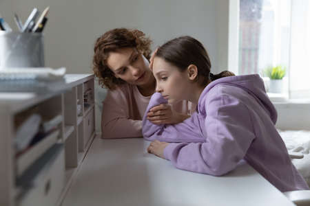 Loving Caucasian mom comfort support unhappy teenage 13s daughter feeling lonely at home. Caring mother cheer sad teen girl child suffering from school discrimination bullying. Loner concept.の写真素材