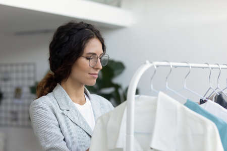 Successful young female fashion designer prepare new clothing collection in home atelier boutique....