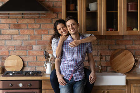 Portrait of happy millennial couple renters tenants relax in own modern kitchen moving in shared home together. Smiling young Caucasian family buyers excited about new dwelling. Real estate concept.の写真素材