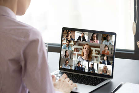 Rear view businesswoman executive engaged in conference with diverse colleagues, sitting at desk,...