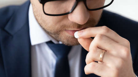 Close up head shot young male manager employee in formal wear taking painkiller pill relieving headache, having aspirin antibiotic feeling first grippe symptoms in office, healthcare vitamins concept.の写真素材