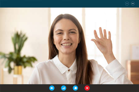 Laptop display close up view smiling pretty millennial woman making hello hi gesture, waving hand, welcoming partner client friend at online video call, starting internet virtual event conference.の写真素材