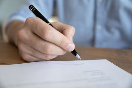 Close up male hand holding pen signing life or health insurance, put signature affirm legal paper...