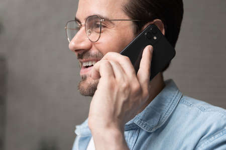 Close up head shot happy handsome 30s man in eyewear holding mobile call conversation, enjoying...