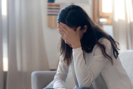 Enough from me... Frustrated depressed young woman or teenager sitting on couch at home crying...
