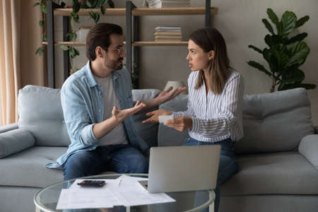Unhappy couple manage household finances argue have problems paying bills or taxes online at home....