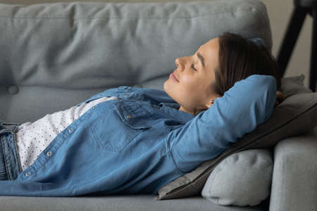 Close up of cam young Caucasian woman lying on comfortable couch at home sleep or take nap. Tired...