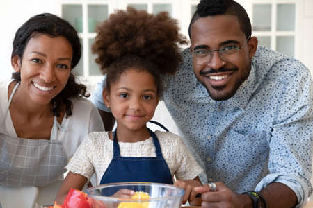 Lunch for mommy and daddy. Portrait of happy black family at modern kitchen, glad african tween girl...