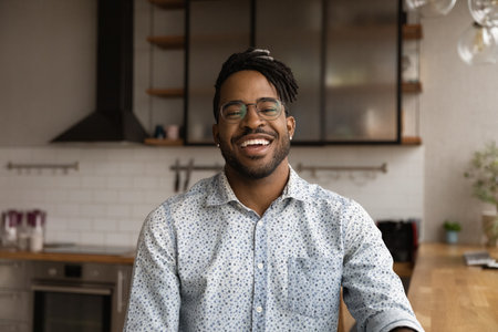 Close up headshot portrait of smiling biracial man in glasses have fun talking on video call at...
