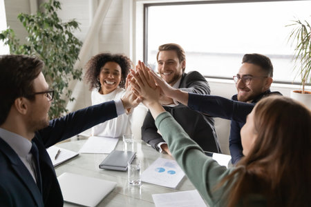Close up of excited multiracial businesspeople give high five show team unity and motivation for...