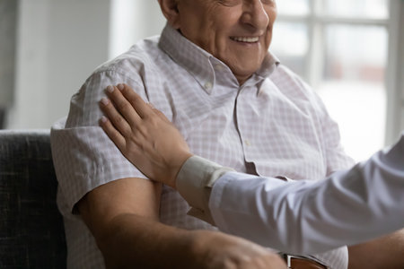 Supportive female doctor hand gentle caress shoulder of smiling aged male ensure in good effect of proposed treatment. Attentive gp give hope motivation belief in recovery to old man patient. Close upの写真素材