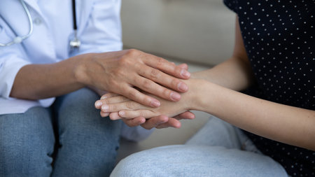 Benevolent female doctor nurse hands holding covering palms of woman patient supporting comforting consoling. Sick young lady receiving empathy compassion of attending physician. Close up cropped viewの写真素材