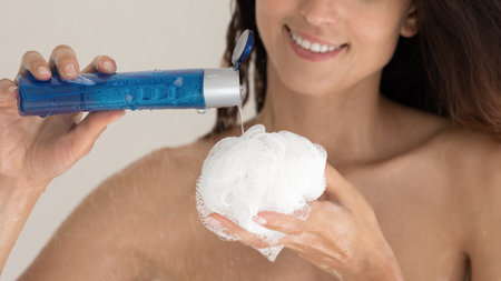 Crop close up of happy woman squeeze apply natural odorant foamy gel of puff having shower in home...
