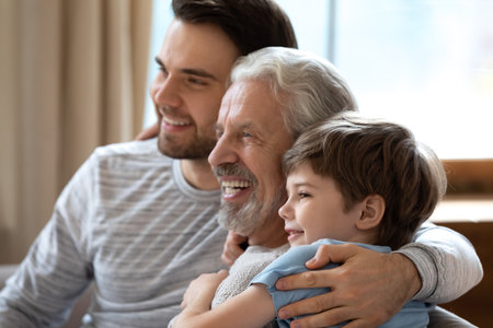 Close up of smiling boy, young father and elderly grandfather relax together in cozy home on...