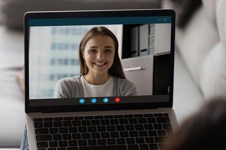 Close up of smiling Caucasian woman on laptop screen engaged in online digital webcam conference. Female colleagues talk speak on video call on computer, have distant virtual meeting on gadget.の写真素材