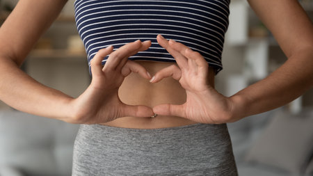 Crop close up of fit woman in sportswear show heart love hand gesture or sign, enjoy sporty life or training activity. Slim female demonstrate sport toned body. Dieting, healthy lifestyle concept.の写真素材