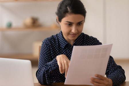 Interested indian woman customer study purchase proposal letter received by mail. Young mixed race...