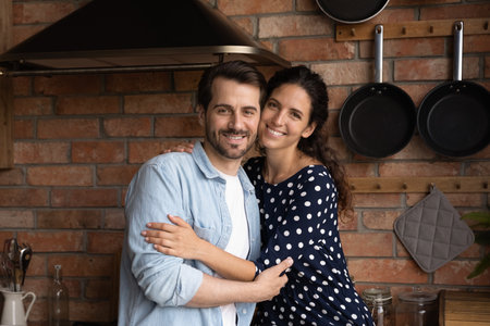Portrait of smiling young Caucasian man and woman hug cuddle excited moving in to new home together. Happy millennial couple show love and care, feel overjoyed relocate to own house. Rent concept.の写真素材