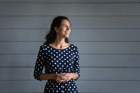 Smiling young Caucasian woman isolated on grey wall background look in distance thinking dreaming. Excited millennial female imagine or visualize happy future or opportunities. Vision concept.の写真素材