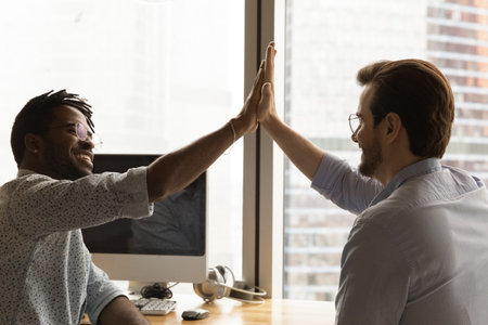 Give me five. Diverse colleagues black and caucasian managers employees join hands high celebrate...