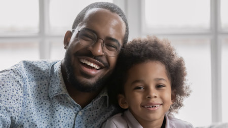 Head shot portrait overjoyed African American father wearing glasses and little son looking at camera, excited dad and adorable toddler boy posing for photo at home, having fun, god family relationsの写真素材