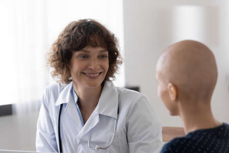 Happy woman doctor talk with hairless female struggle with oncology, support comfort at consultation. Smiling GP feel overjoyed with good treatment, beat cancer with patient. Recovery concept.の写真素材