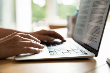 Crop close up of woman sit at desk use modern laptop gadget texting typing on keyboard. Female...