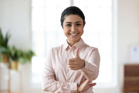 Confident young Indian woman making thumb up approval gesture. Happy businesswoman showing like at camera. Customer satisfied with good quality or service. Feedback, recommendation conceptの写真素材