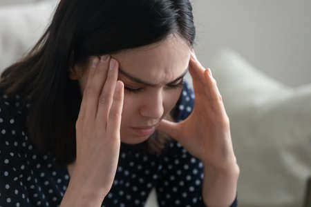 Close up of young asian female sit alone rub temples having headache migraine suffering from sudden...