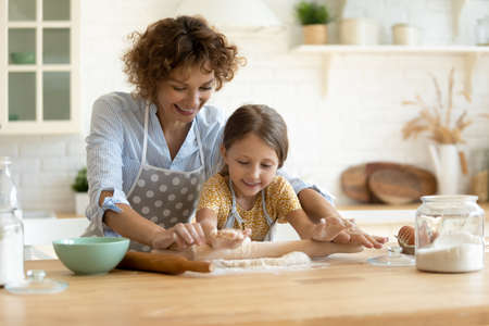 In four hands. Loving family of single mother small daughter child baking cake pastries cooking pie...